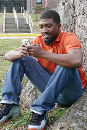 Man sitting on tree smiling at phone